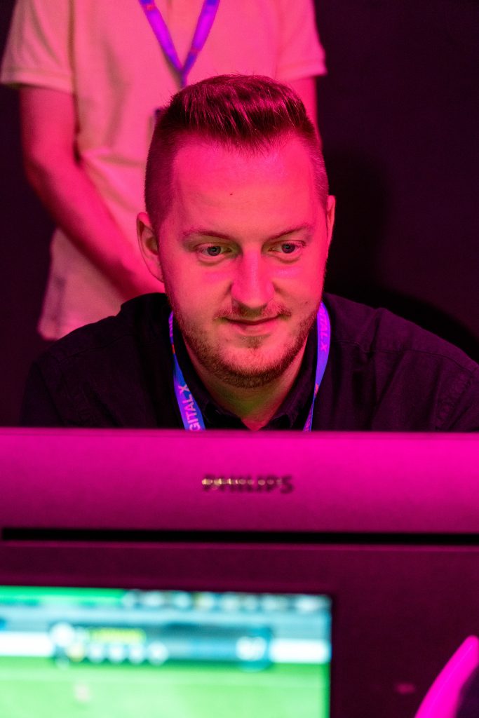 digital-x-2024-20 Konzentrierter Spieler in der eFußball-Arena auf der Digital X 2024.