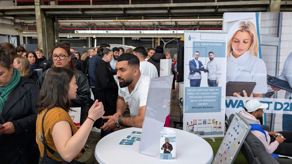 PXL_20260326_102303448.MP Menschen im Gespräch bei der Jobmesse in Düsseldorf neben der eFußball-Arena.
