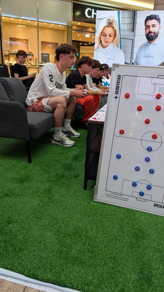 PXL_20260704_175206626.TS-000.MP Vier Spieler sitzen konuentriert in der eFußball-Arena als Recruiting-Maßnahme für D.A. Direktvertrieb im Centro Oberhausen.